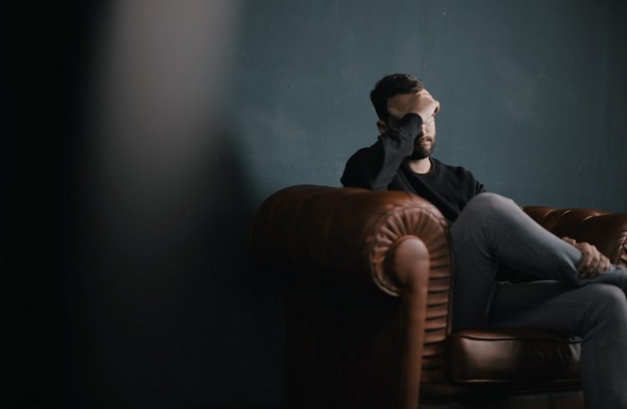 Reduce Migraine Symptoms - man sitting quietly holding his head with migraine